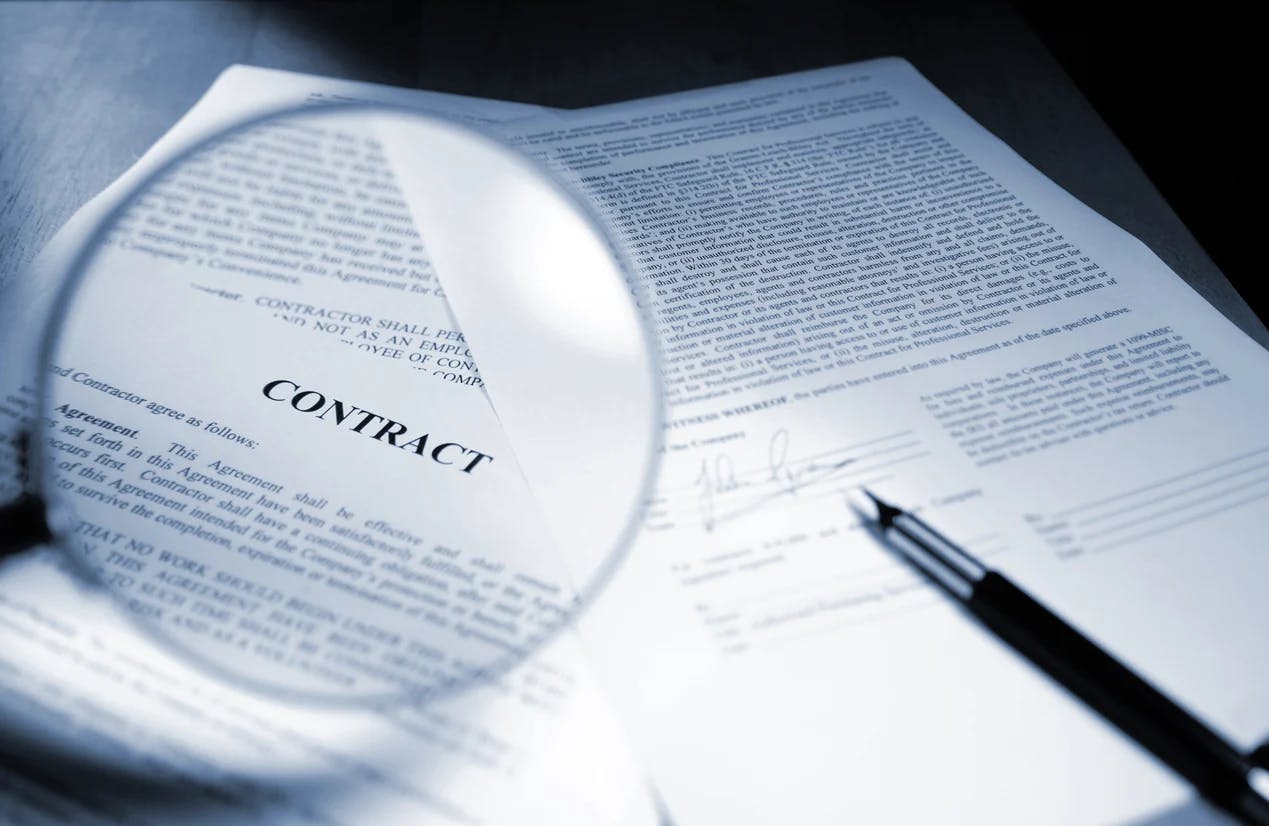 A magnifying glass enlarges the text of a legal agreement during the contract review process.