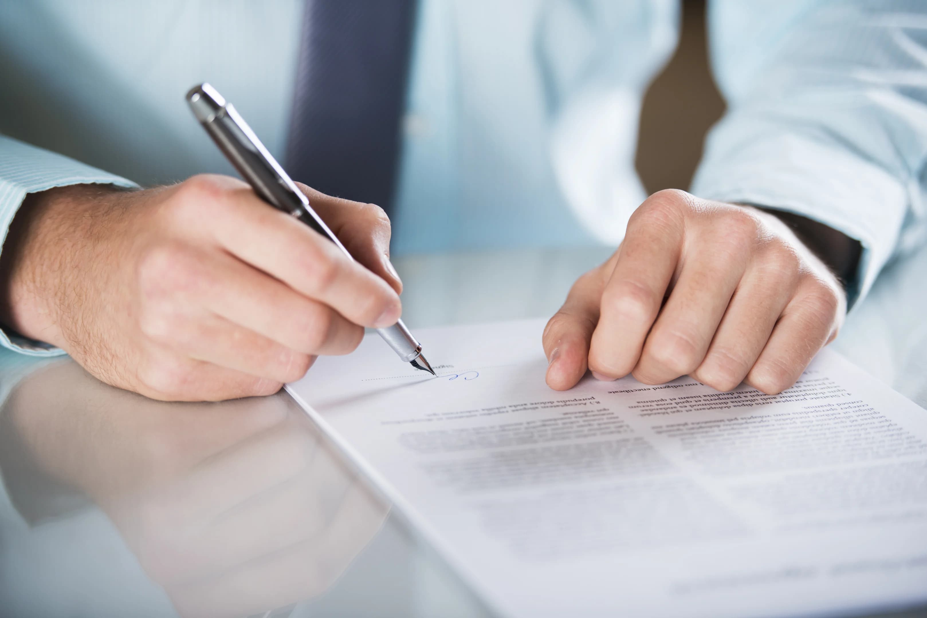 A man’s hands signing a document that could be a confidentiality agreement or NDA