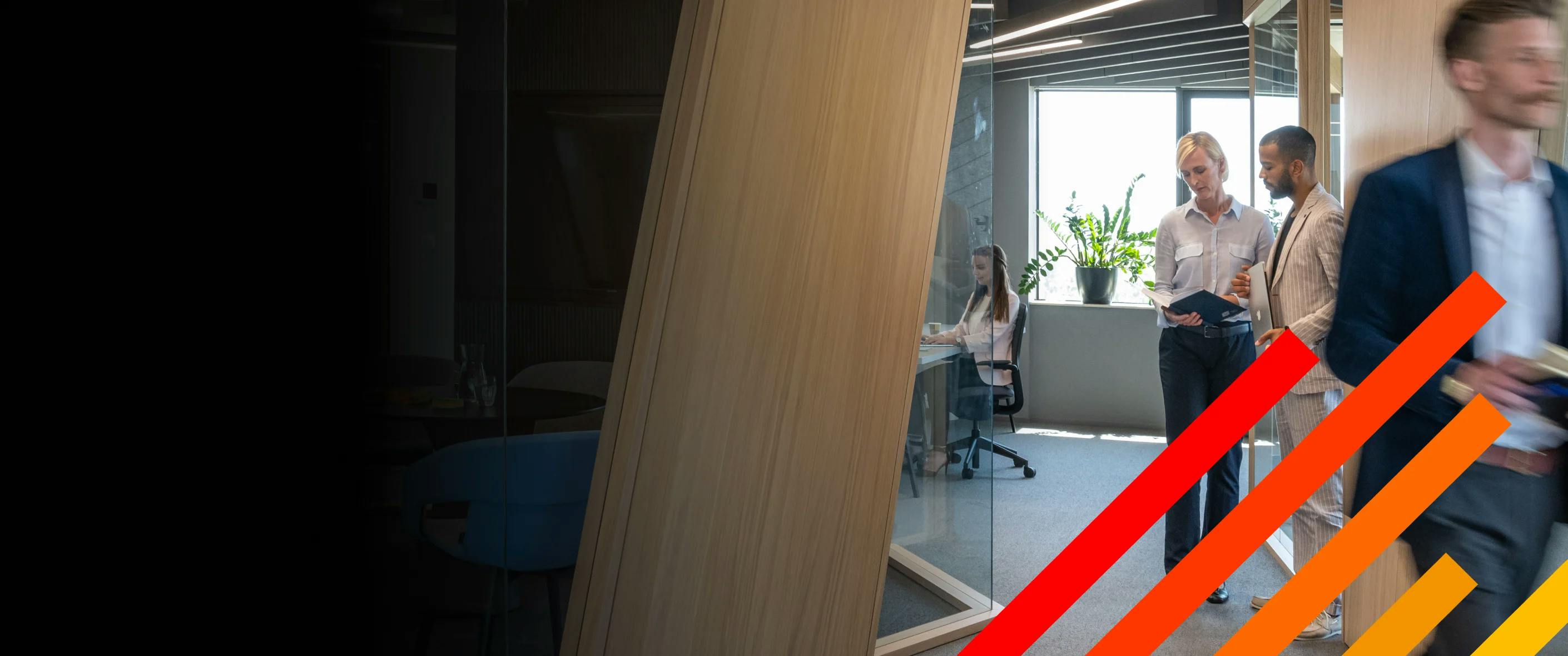 Scene at a law firm with two colleagues standing and consulting with another walking by and a fourth working at her desk in the background