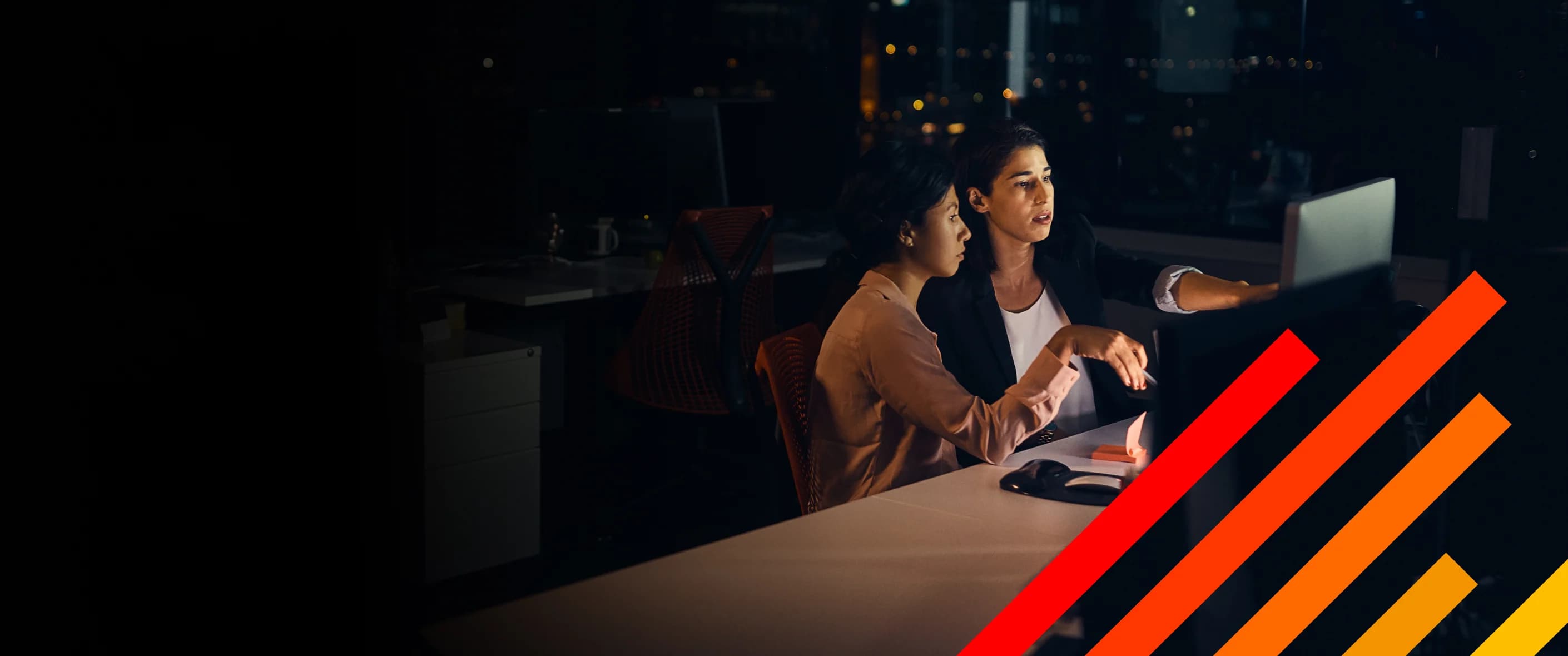 Two legal professionals consulting in front of a computer after hours.